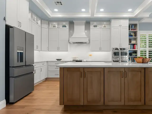 Transitional kitchen remodel with white shaker cabinets, a white range hood, a stained wood island with a white top and a coffered ceiling
