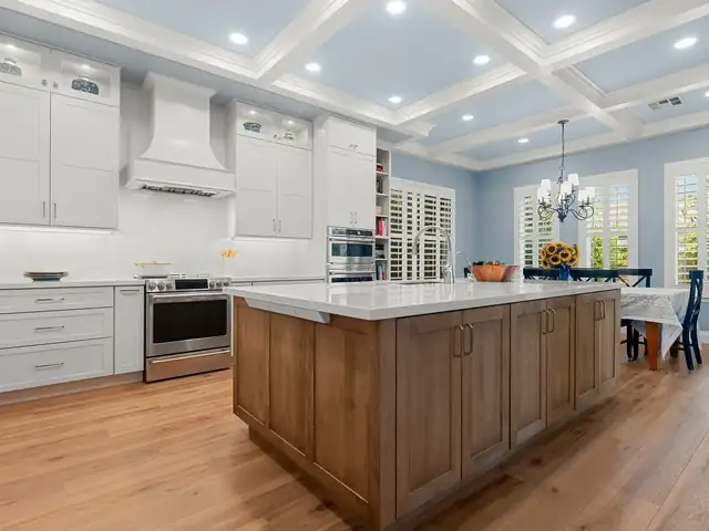 Transitional kitchen with white shaker cabinets, a coffered ceiling, a stained wood island with a white top and a wide-plank wood floor