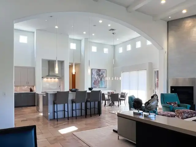 Cave Creek updated ranch kitchen open to the great room, with gray cabinets, a stainless hood and island seating seen through an arched opening