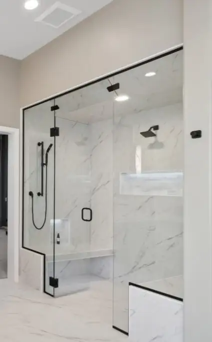Miller primary bath steam shower with frameless glass, white marble-look walls, a built-in bench and niche, and black fixtures
